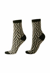 Chaussettes à motifs noir et blanc avec un design en chevrons, présentant un revers côtelé noir et des talons et orteils noirs unis.