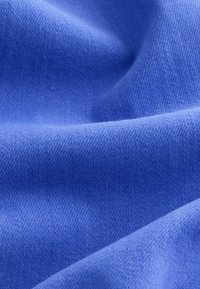 Tissu bleu doux avec une texture fine tricotée, montrant de légers plis et des détails de surface lisses.