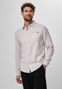 Ljust rosa långärmad skjorta i texturerad tyg med knapp-down krage, bröstficka och subtil varumärkesetikett. Kombinerad med svarta byxor.
