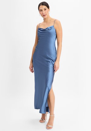 Satin blaues Maxikleid mit einem gerafften Ausschnitt, dünnen Trägern und einem Seitenschlitz. Der Stoff hat eine glatte, glänzende Oberfläche. Ergänzt durch silberne Absätze.