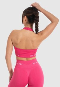 Sujeción deportiva de color rosa con canales y leggings de cintura alta a juego, con detalles de logotipo en blanco, diseño ajustado y material suave.