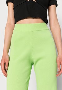 As calças de malha canelada verdes apresentam uma cintura alta e um design de perna reta, com uma textura suave e uma cintura lisa.