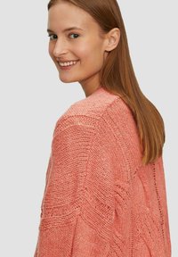 Strickpullover aus strukturiertem Korallengarn mit lockerer Passform und dezenten diagonalen Mustern. Über die Schulter getragen, zeigt er ein weiches, lässiges Design.