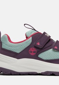 Lila och teal sneakers med mesh-överdel, rosa accenter, kardborreband och en vit mellansula. Har logotyp på sidan och texturerad sula.
