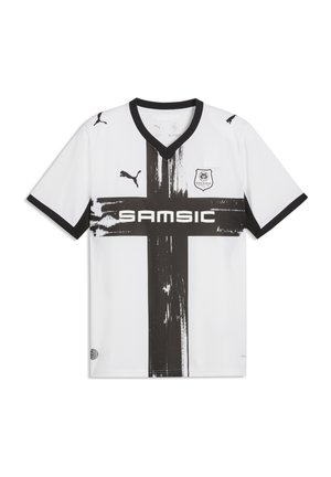 Biały strój piłkarski z czarnym dekoltem w kształcie litery V i krawędziami na rękawach, dużym czarnym malowanym krzyżem, logo Puma, herbem Stade Rennais oraz tekstem sponsora "SAMSIC".