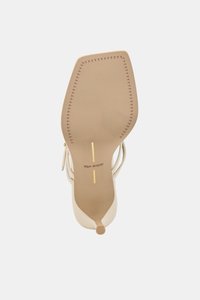 Beige sandal med høye hæler, firkantet tå, ankelstropp og "dolce vita"-merke på sålen, sett nedenfra.