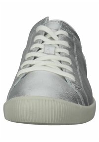 Zapatilla metálica plateada con cordones blancos, punta redondeada y suela de goma texturizada. Presenta superficies lisas y ligeramente arrugadas.