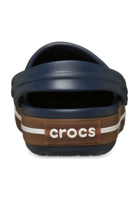 Zuecos Crocs azul marino con base marrón, línea blanca y logo, con parte trasera redondeada y plantilla texturizada para mayor comodidad.