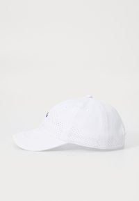Gorra de béisbol blanca con paneles laterales perforados, ala curvada y un pequeño logotipo azul en el frente. Hecha de tela ligera, diseño estructurado.