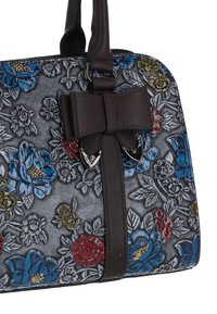 Sac à main à motif floral en gris avec des fleurs bleues, rouges et jaunes. Dispose d'un nœud en cuir marron et d'accents en métal argenté.