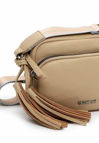Beige nahkalaukku olkaimella, jossa on teksturoitu pinta, vetoketjulliset taskut ja koristeelliset tupsut; säädettävä hihna logotietoja.