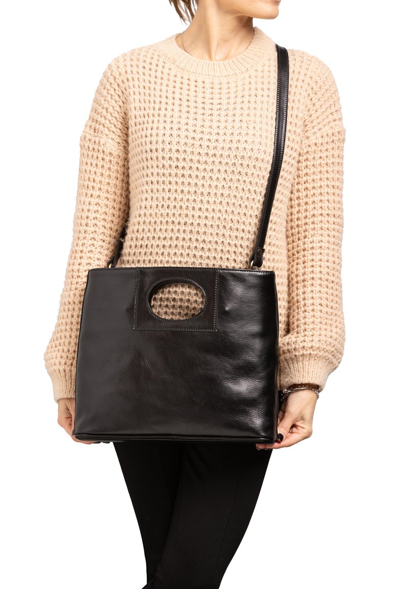 Borsa a tracolla in pelle nera con finitura liscia, forma rettangolare e manico con taglio circolare. La tracolla è regolabile per essere indossata a tracolla.