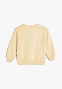 Sudadera beige clara hecha de tela suave, con mangas largas, puños acanalados y un cuello redondo. Textura suave con un corte relajado.