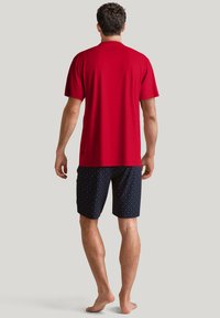 Rode T-shirt met korte mouwen en een soepele textuur, gecombineerd met donkerblauwe shorts met een klein, multicolor stippenpatroon.