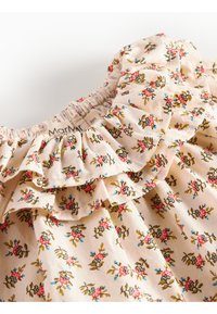 Blomstrete babykjole med volang rundt halsen, har små rosa og blå blomster på en kremfarget bakgrunn, laget av myk stoff. Størrelsesmerke synlig.