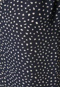 Tessuto blu navy con un motivo testurizzato di forme bianche irregolari, creando un design visivamente interessante adatto per l'abbigliamento.