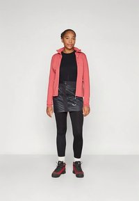 Ροζ φούτερ με φερμουάρ, μαύρο μακρυμάνικο τοπ, μαύρη μίνι φούστα, μαύρα κολάν και παπούτσια με κόκκινες λεπτομέρειες. Λείο ύφασμα, αθλητική εφαρμογή συνολικά.