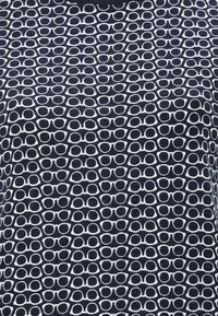 Marinblått tyg med ett vitt tryck av överlappande solglasögon i olika storlekar, med en slät struktur och ett upprepande mönster.