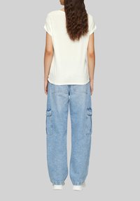 Witte korte mouwen t-shirt en lichtblauwe cargobroek met zijzakken, gedragen met witte sneakers. Zachte textuur, relaxte pasvorm, casual ontwerp.