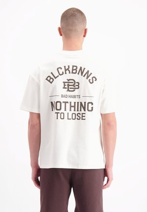 Witte katoenen t-shirt met een grote bruine grafische print op de achterkant met tekst: "BLCKBNNS BAD HABITS NOTHING TO LOSE." Korte mouwen, ontspannen pasvorm.
