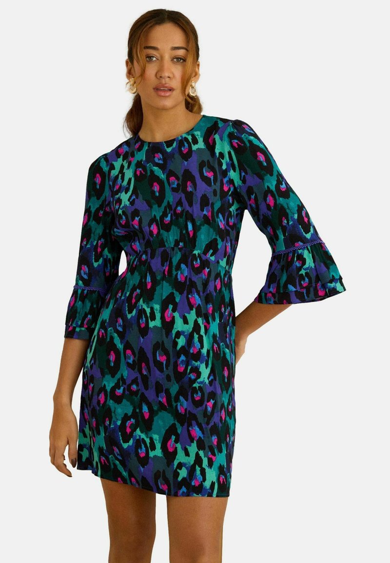 Lühikeste varrukatega kleit erksas mitmevärvilises leopardimustris, rohelise, lilla ja roosa toonidega; iseloomulik on lõhestatud vöökoht ja lehvivate varrukatega disain.