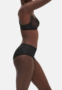 Set di lingerie in pizzo nero composto da un bralette con spalline regolabili e culotte a vita alta, entrambi con intricati motivi a foglia.
