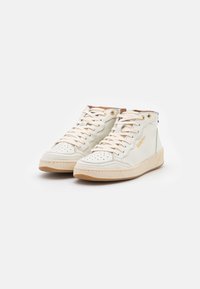 Hochtop-Sneaker aus cremefarbenem Leder mit perforierter Zehe, tanfarbenen Akzenten, beiger Sohle und Schnürdesign. Merkmale sind goldene Ösen und Logo-Detail.
