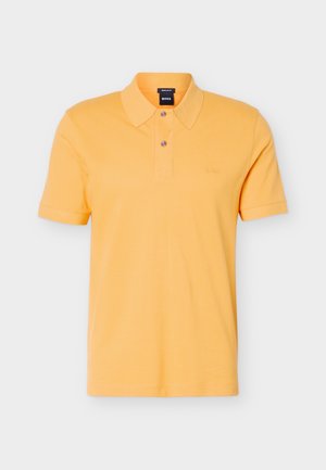 Κίτρινο πόλο μπλουζάκι με κοντά μανίκια, δύο κουμπιά, κλασικό γιακά και διακριτικό λογότυπο στο αριστερό μέρος του στήθους, πάνω σε ανοιχτό φόντο.