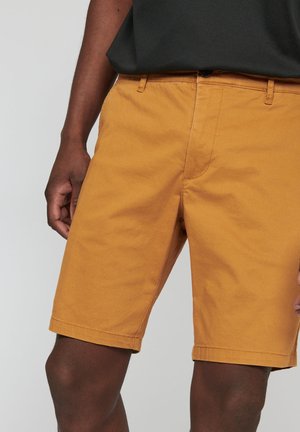 Herrenshorts in Senfgelb aus Baumwoll-Mischgewebe, mit klassischer Passform, Seitentaschen und geradem Saum. Glatte Textur, keine sichtbaren Muster.