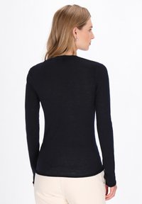 Langsleeve marineblauw top met een getailleerde silhouet, een zachte textuur en een ronde halslijn, met een subtiele glans en minimale naden.
