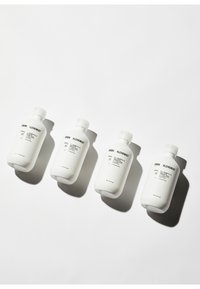 Quattro bottiglie bianche in plastica con tappi a vite presentano un testo minimalista in nero. Il design è arrotondato con una finitura liscia e opaca.