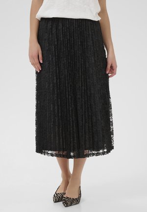 Schwarzer, gefalteter Spitzenrock mit floralem Muster, der bis zur Mitte der Wade reicht, kombiniert mit schwarz-weißen Zebra-Print-Absätzen. Glatte Textur, elegantes Design.