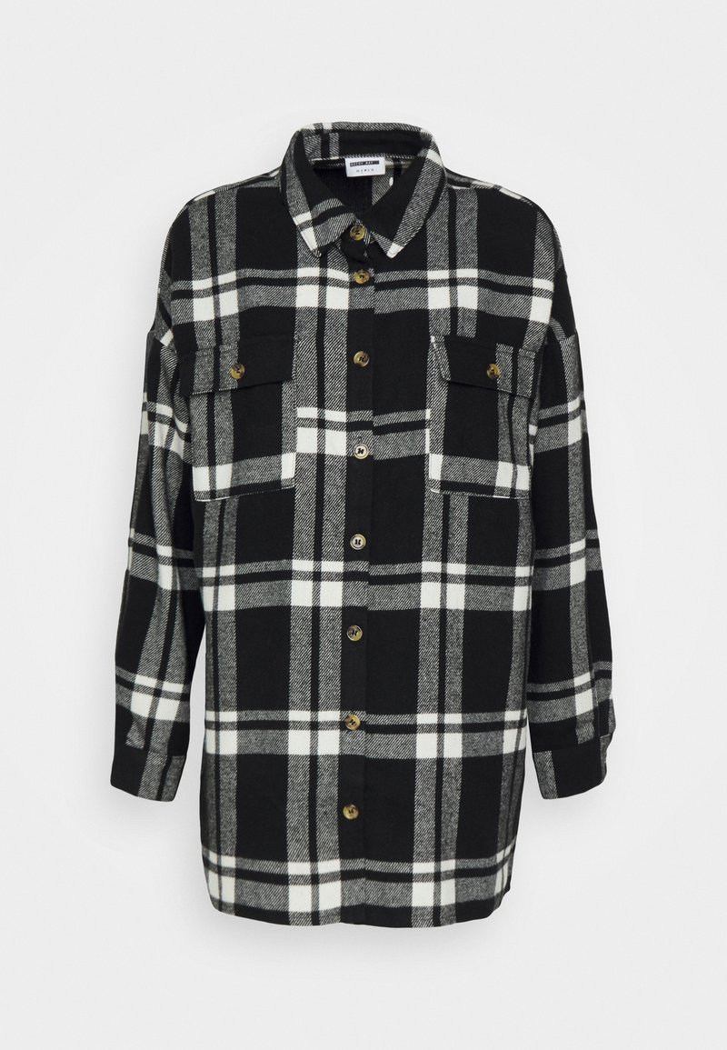 Camicia di flanella a scacchi bianco e nero con colletto, due tasche sul petto e chiusura a bottoni. Tessuto morbido e vestibilità rilassata con maniche lunghe.