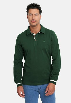 Polo de manga larga color verde oscuro con cuello, tapeta de tres botones y puños con rayas blancas. Presenta un logo bordado en el pecho.