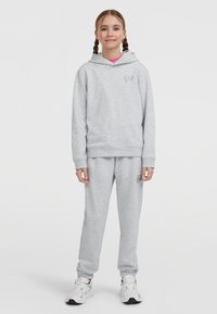 Felpa grigia con tasca frontale e logo a cuore ricamato, abbinata a pantaloni della tuta grigi coordinati, entrambi in tessuto misto cotone.