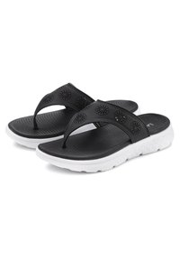 Musta flip-flop-sandaalit, joissa on reikärakenne hihnassa, teksturoitu musta pohja ja valkoinen pehmustettu pohja. Sopii arkikäyttöön.