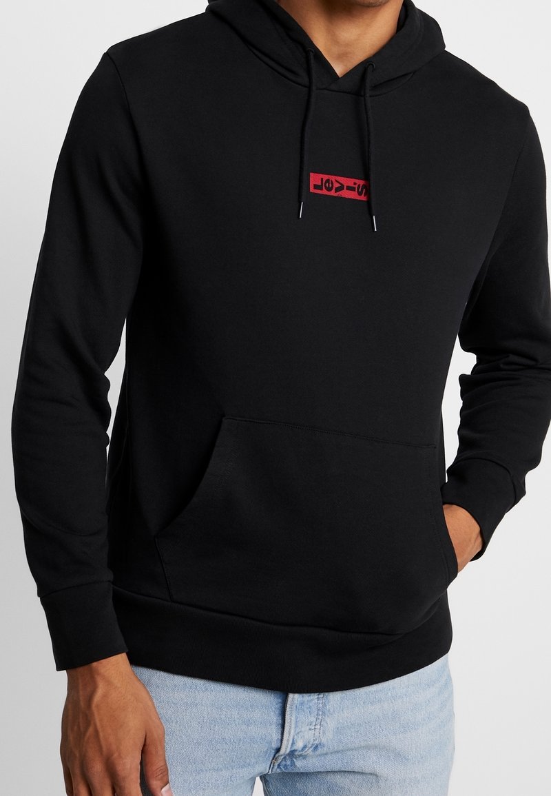 Sweat-shirt à capuche noir en coton, avec un logo rectangulaire rouge sur la poitrine, une poche frontale et des poignets côtelés.
