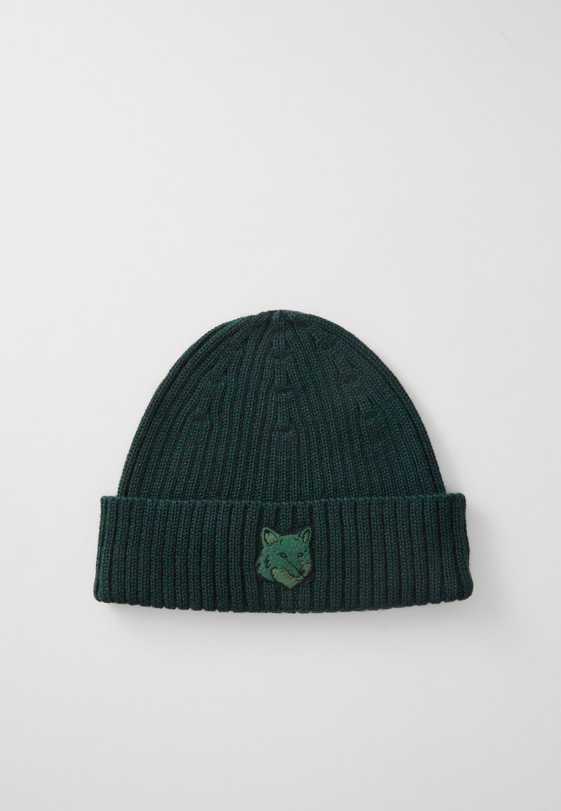 Căciulă tricotată verde, cu textură ribbată. Are o manșetă îndoită și un logo brodat cu capul unei vulpi pe față.