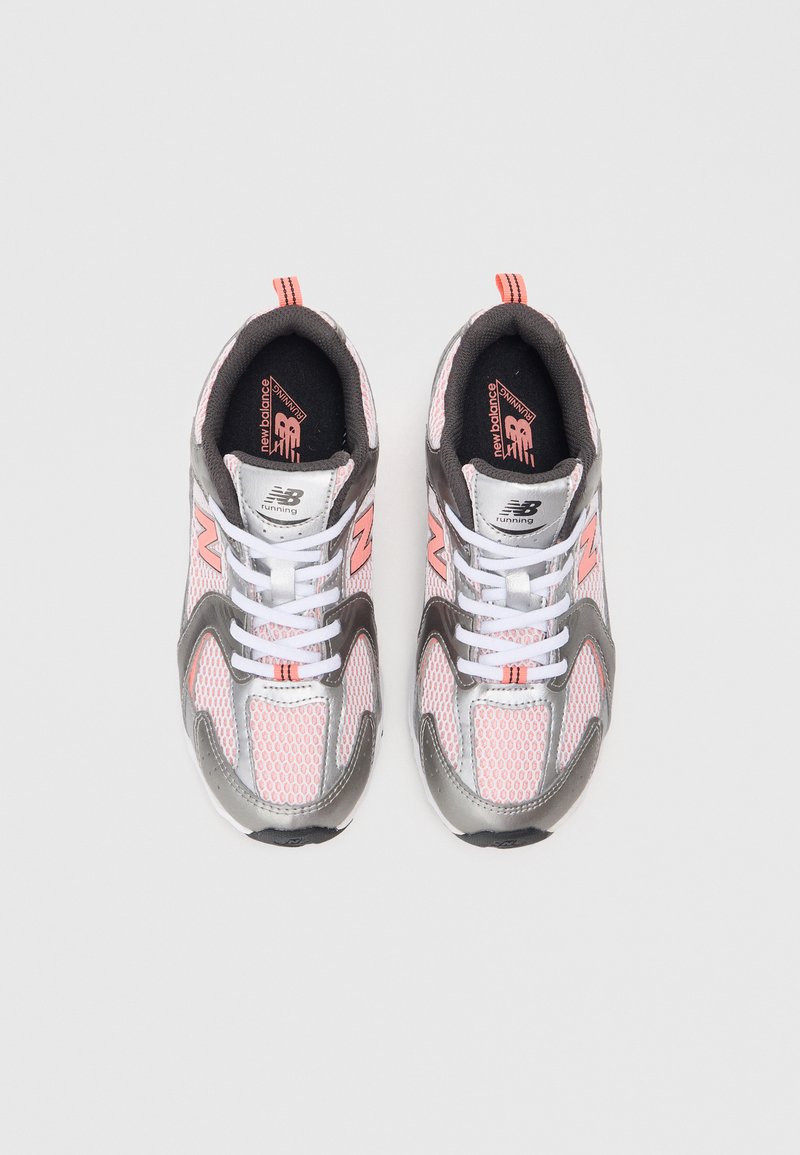 Chaussures de sport grises et roses avec tige en mesh, semelle en caoutchouc et lacets blancs. Présente le logo New Balance et des accents réfléchissants.