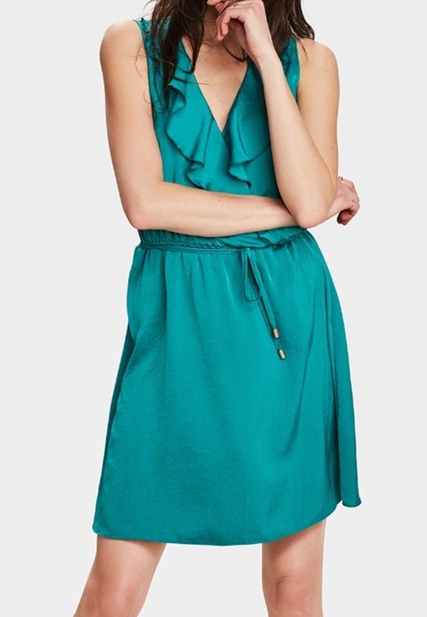 Teal sleeveless dress with ruffled neckline, cinched waist, and drawstring detail. Soft fabric with a smooth texture. Above-the-knee length.
