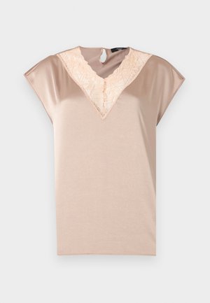 Haut à manches courtes en tissu beige doux, avec un col en dentelle en forme de V et un détail dos en forme d'œillet. Texture lisse avec une coupe décontractée.