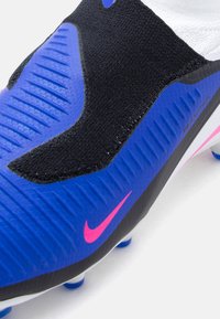 Μπλε και μαύρο ποδοσφαιρικό παπούτσι με υφασμένη επιφάνεια, ροζ λογότυπο Nike, μαύρο πλεκτό επάνω μέρος και λευκή σόλα με μπλε καρφιά.