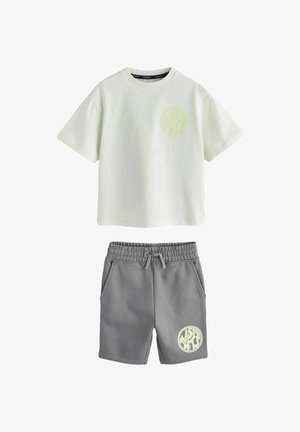 Kortærmet offwhite T-shirt med rund hals og grå snøre-shorts, begge med et lille rundt gult logo-print.
