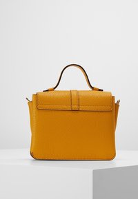 Strukturalna skórzana torebka w jaskrawożółtym kolorze, wyposażona w górny uchwyt, klapę zapiętą na zatrzask oraz fakturowaną powierzchnię z ozdobnymi przeszyciami.