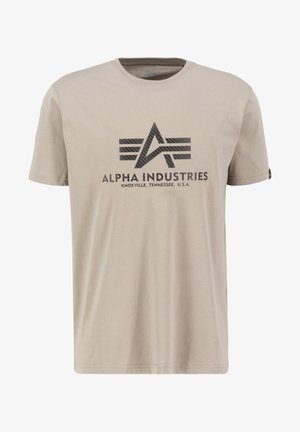 Beige cotton t-shirt with short sleeves, featuring a black graphic logo and text "ALPHA INDUSTRIES" on the front. Smooth texture.