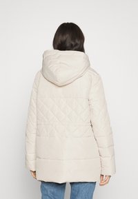 Beige gewatteerde pufferjas met een capuchon, met een ruitenpatroon, lange mouwen en een ontspannen pasvorm.