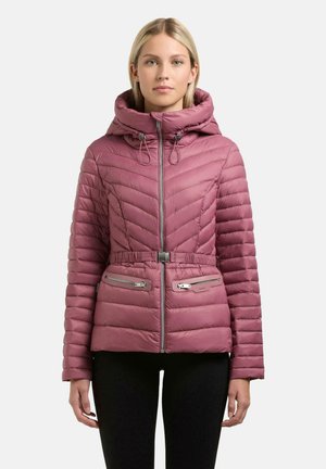 Kobieta ubrana w różową pikowaną kurtkę z wysokim kołnierzem, kapturem, zamkiem z przodu, paskiem i zapinanymi kieszeniami, stojąca na jednolitym tle.