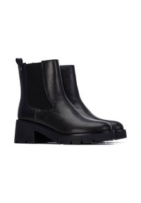 Botines negros con piel suave, paneles laterales elásticos, tacón grueso negro y suela texturizada para un mayor agarre.