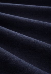 Tessuto blu navy con una superficie liscia, caratterizzato da morbidi drappeggi e una trama uniforme e regolare. Nessun motivo o dettaglio in metallo visibile.