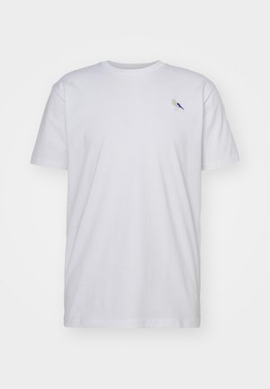 T-shirt branca de algodão com mangas curtas, apresentando uma pequena ilustração de um pássaro em bege e azul na área do peito esquerdo.